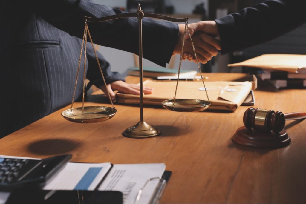 men-shaking-hands-beside-balance-scales